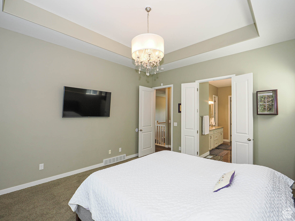 Bedroom featuring a chandelier, dark carpet, and ensuite bathroom