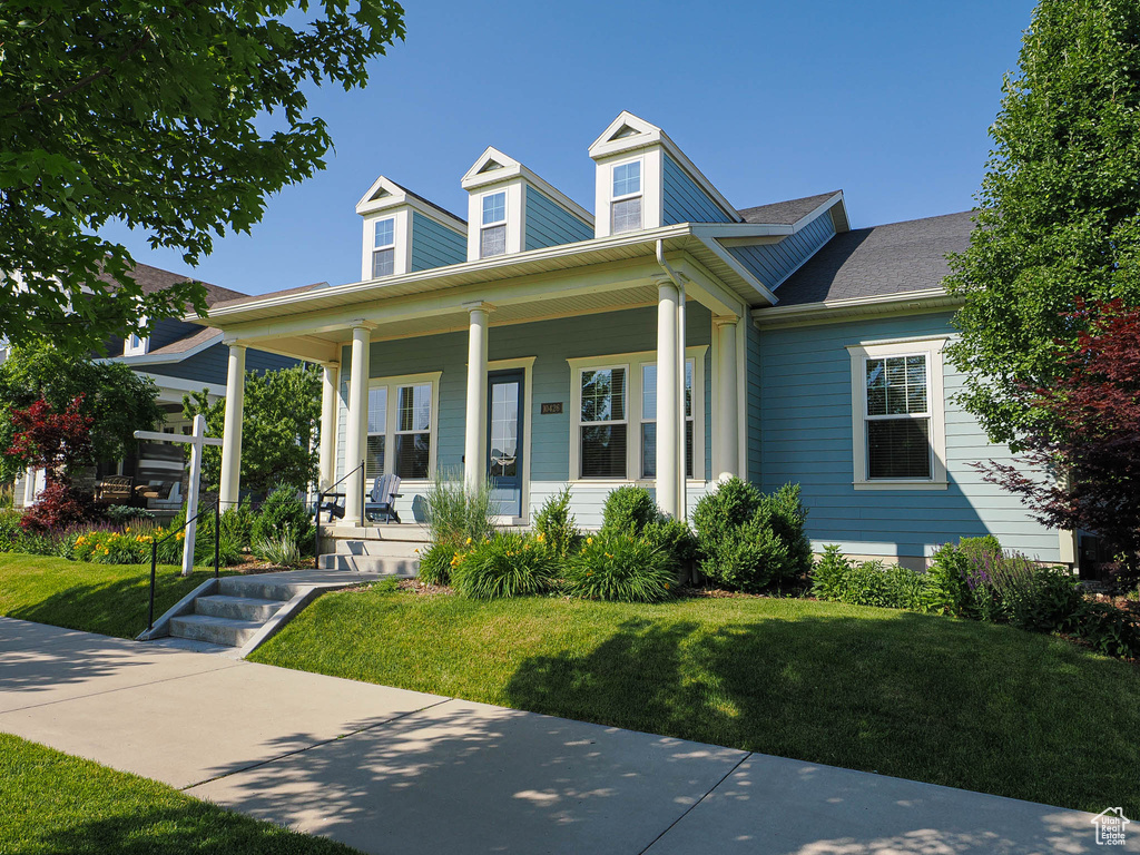 View of front of property featuring covered porch, a front lawn, and roof with shingles