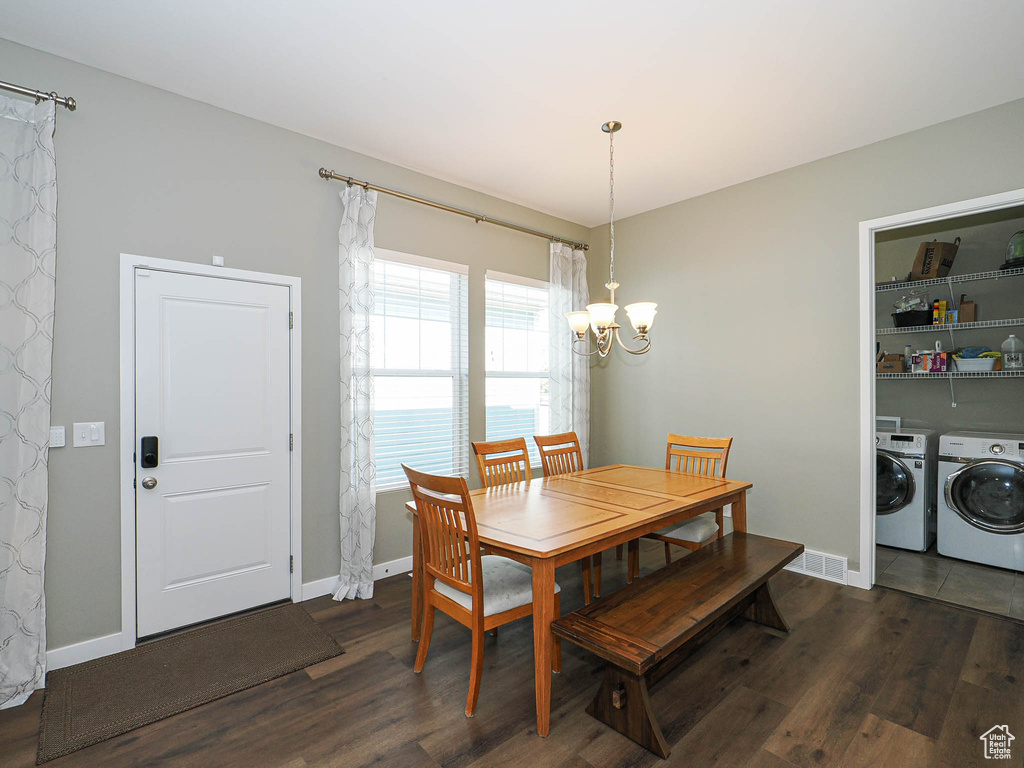 Dining room with separate washer and dryer, a chandelier, and dark wood-style flooring