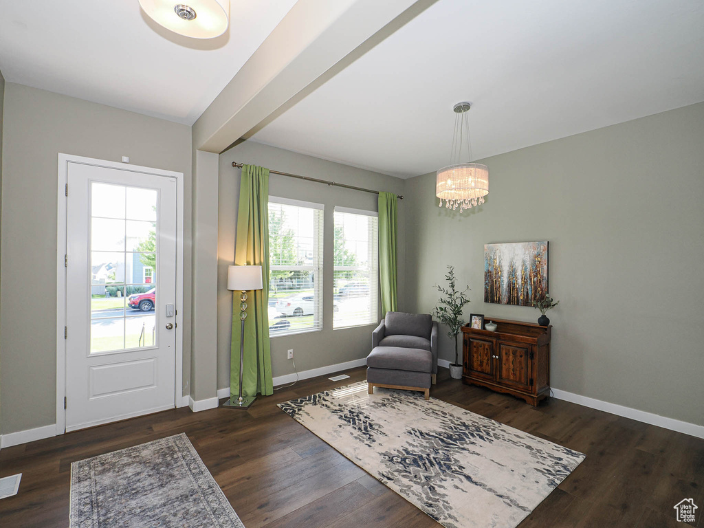 Sitting room with a chandelier, wood finished floors, and beamed ceiling