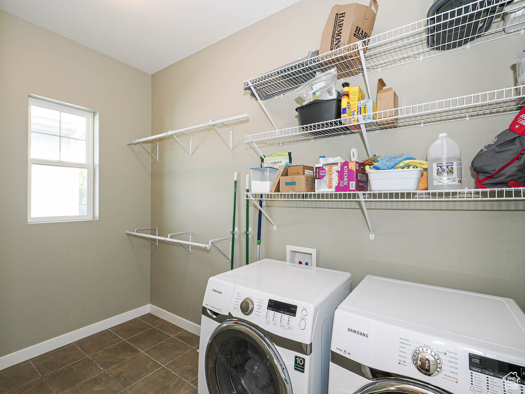 Laundry room with washer and clothes dryer and tile patterned flooring