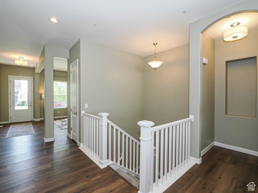 Hall with an upstairs landing, wood finished floors, arched walkways, and recessed lighting