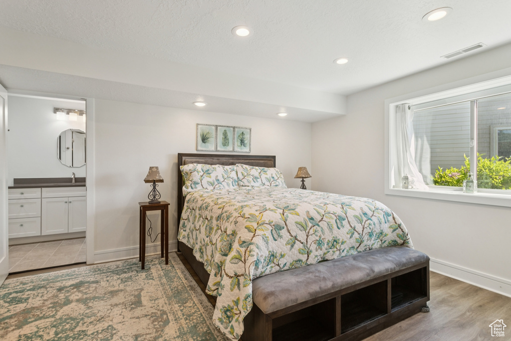 Bedroom with recessed lighting, ensuite bathroom, and wood finished floors