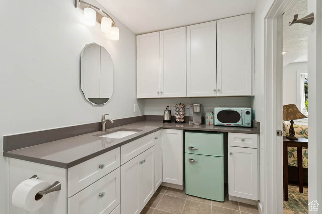 Kitchen with white appliances, white cabinetry, dark countertops, and light tile patterned floors