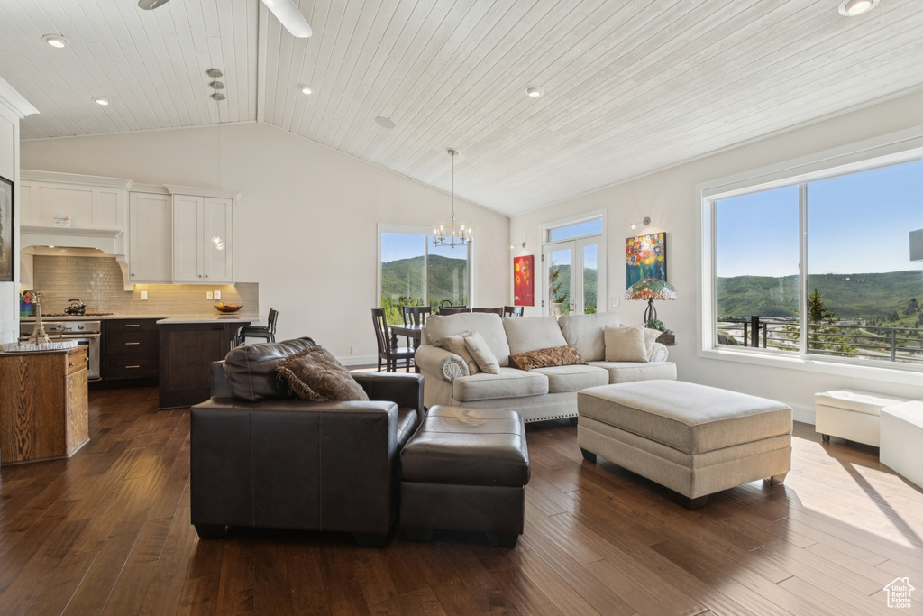 Living room featuring lofted ceiling, dark wood finished floors, a chandelier, a ceiling fan, and a mountain view