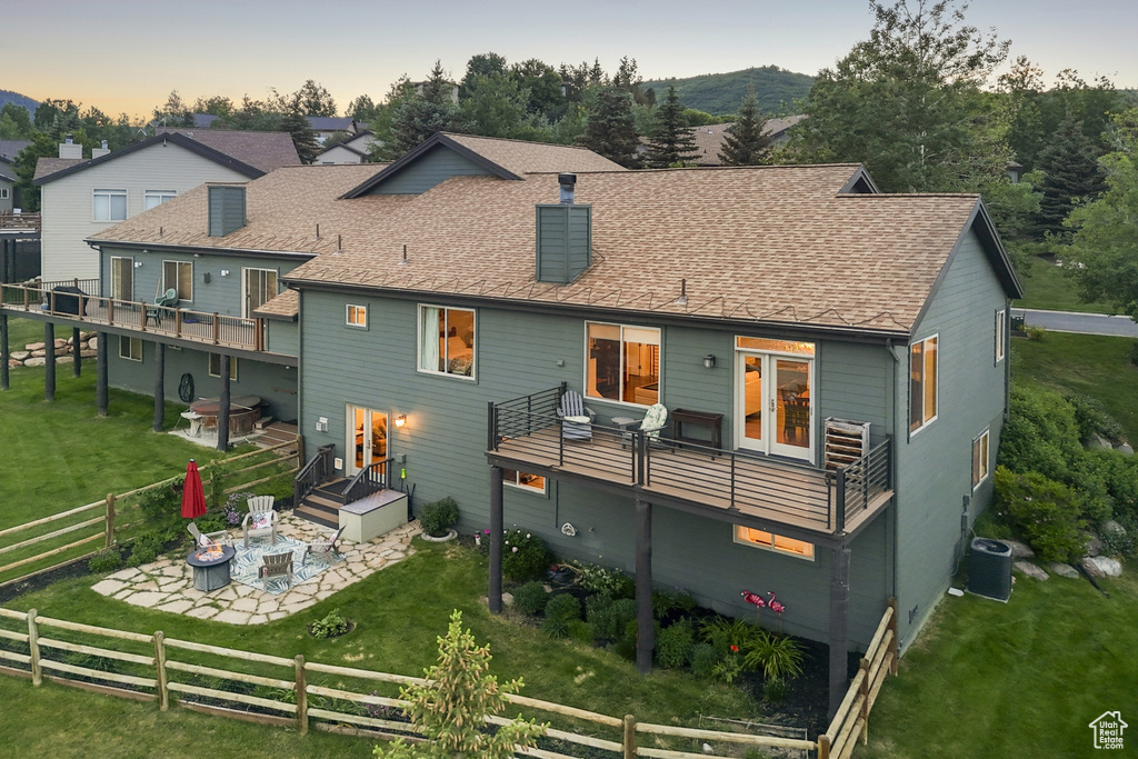 Back of property with a patio, a fenced backyard, a fire pit, a chimney, and roof with shingles