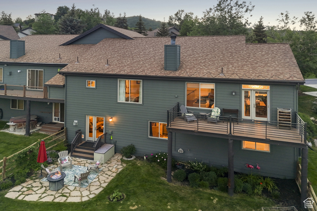 Rear view of house with a balcony, a patio area, a chimney, and a yard