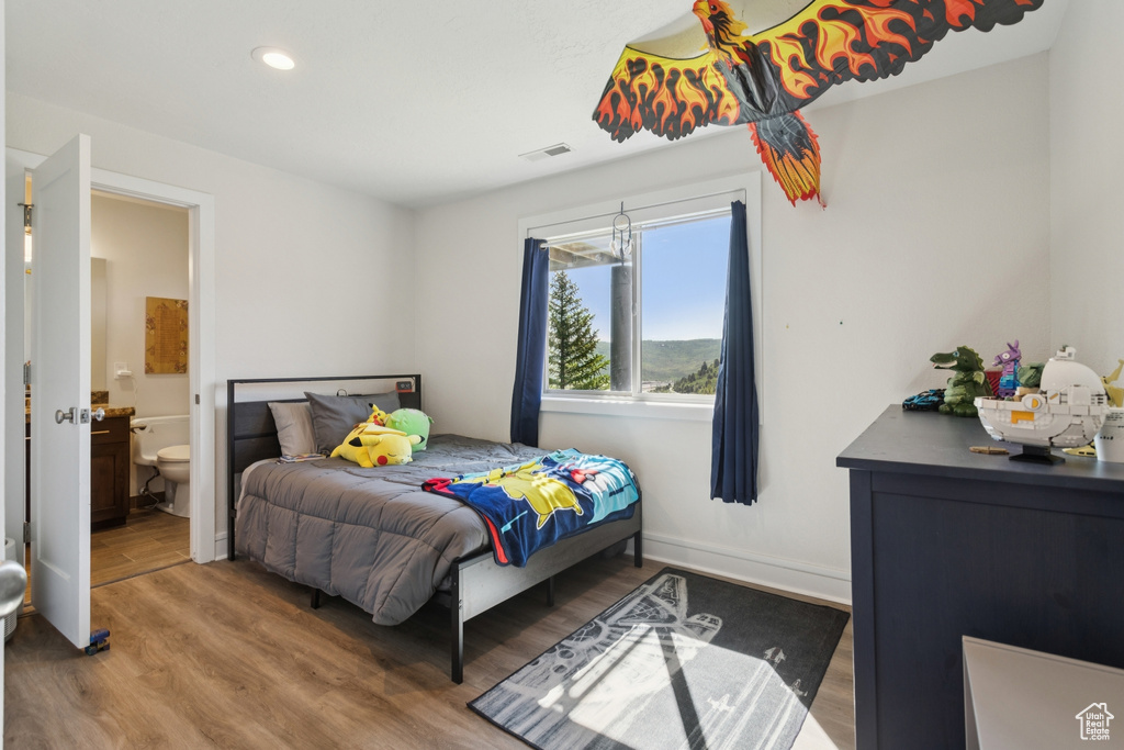 Bedroom with wood finished floors, ensuite bathroom, and recessed lighting
