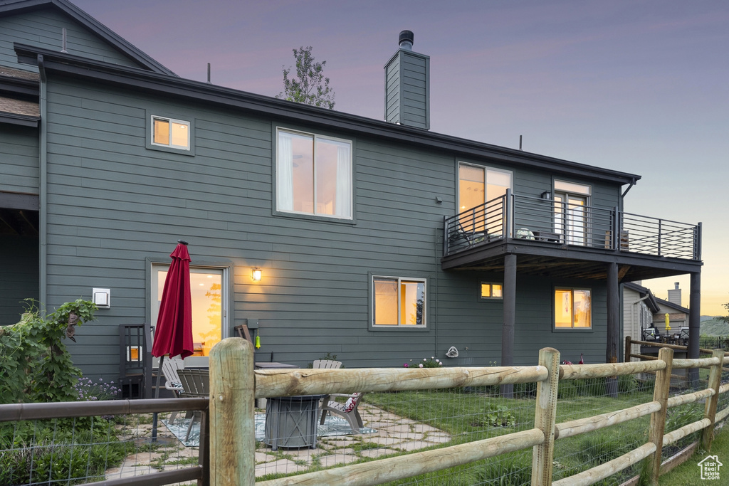 Rear view of property with a balcony, a chimney, and a patio area
