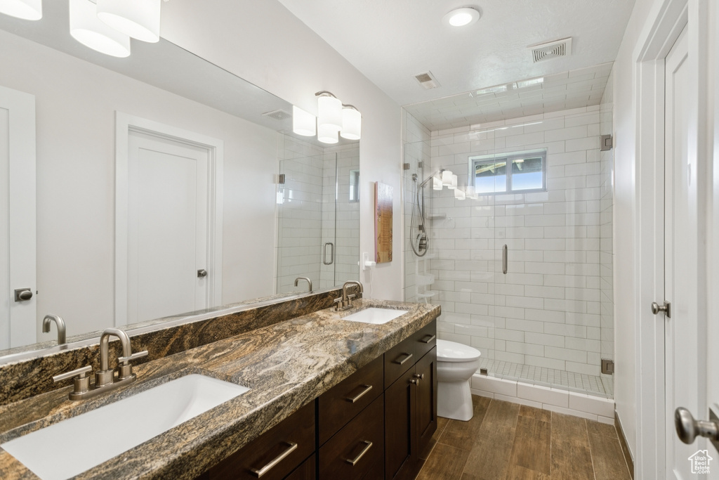 Bathroom featuring wood finished floors, a stall shower, and double vanity
