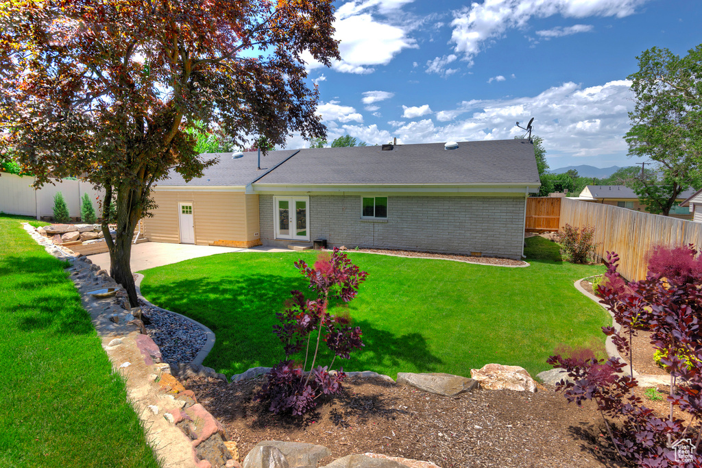 Back of house featuring a fenced backyard, a patio, brick siding, french doors, and roof with shingles