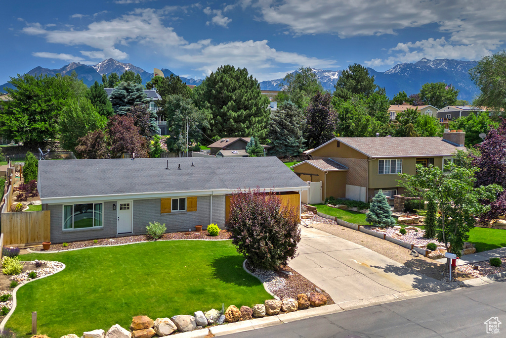 View of front of home featuring a mountain view, driveway, a shingled roof, and brick siding