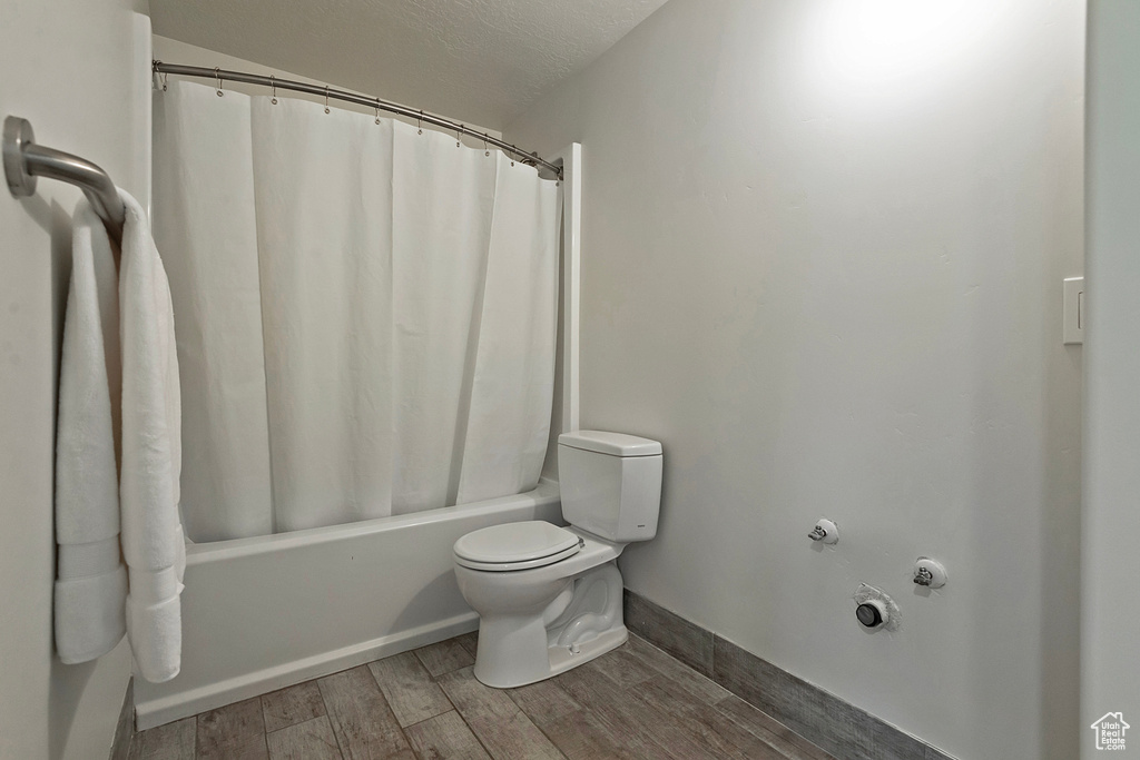 Full bath featuring shower / bathtub combination with curtain and wood finished floors