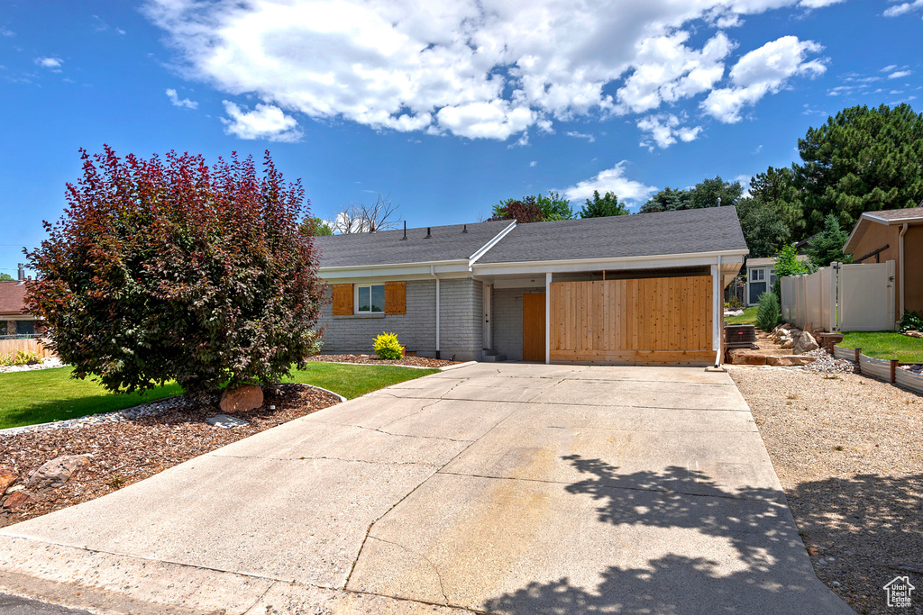 View of front of home featuring concrete driveway, brick siding, and a shingled roof
