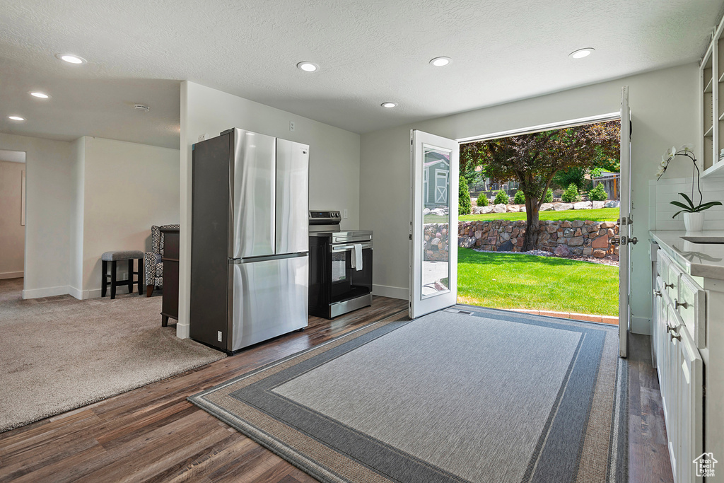 Kitchen featuring appliances with stainless steel finishes, wood finished floors, recessed lighting, a textured ceiling, and white cabinets