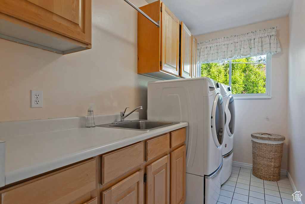 Washroom featuring cabinet space, washer and clothes dryer, and light tile patterned floors