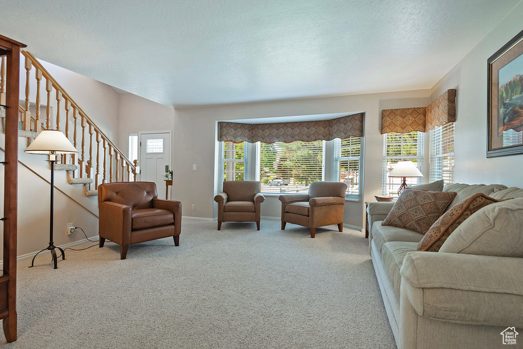Living area with carpet, stairs, and a textured ceiling