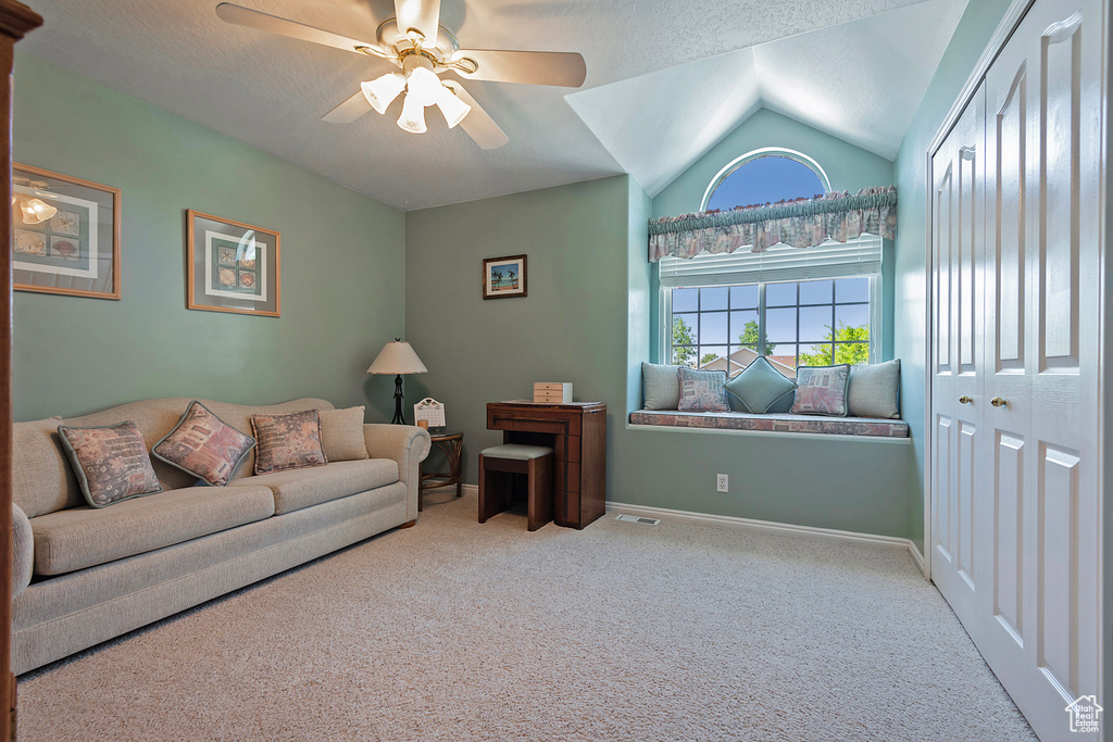 Carpeted living area with a ceiling fan, lofted ceiling, and a textured ceiling