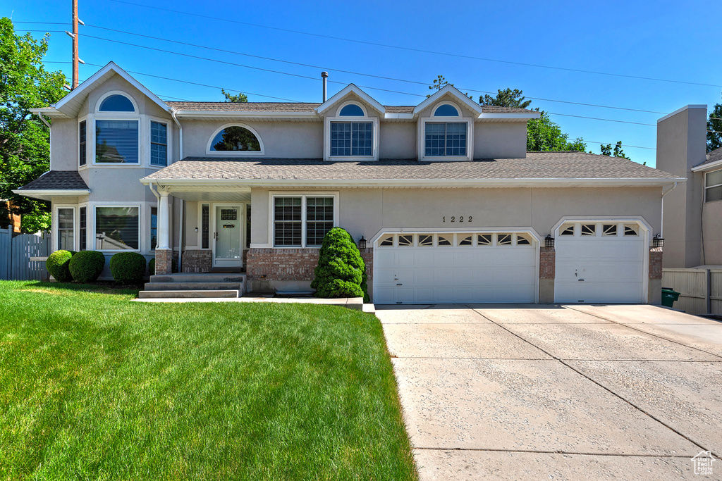 View of front of property featuring an attached garage, concrete driveway, stucco siding, and a front lawn