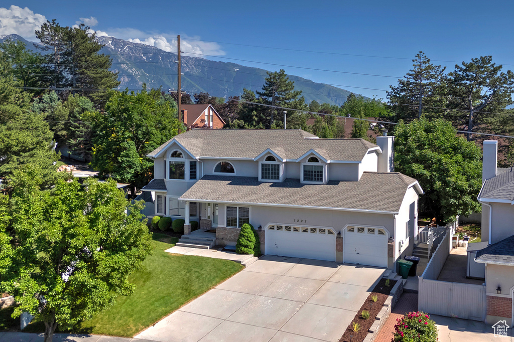 View of front of home featuring concrete driveway, an attached garage, a mountain view, and stucco siding
