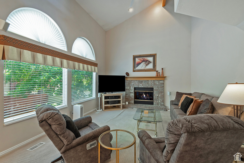 Living area with high vaulted ceiling, carpet floors, and a glass covered fireplace