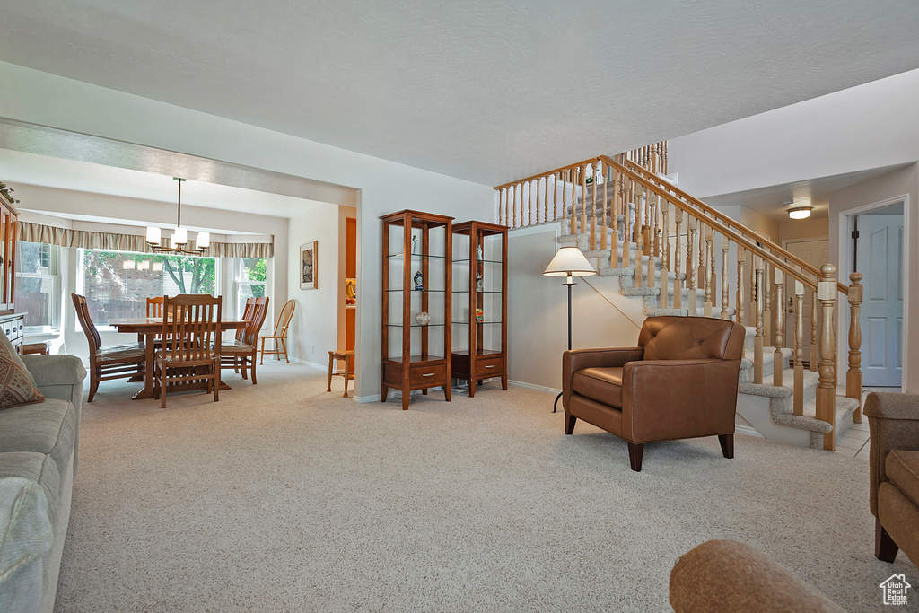 Carpeted living area featuring stairway and a chandelier