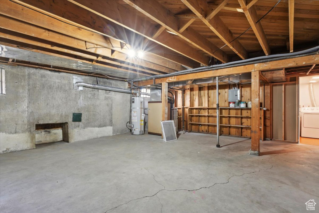 Unfinished basement featuring water heater, washer / clothes dryer, electric panel, and heating unit