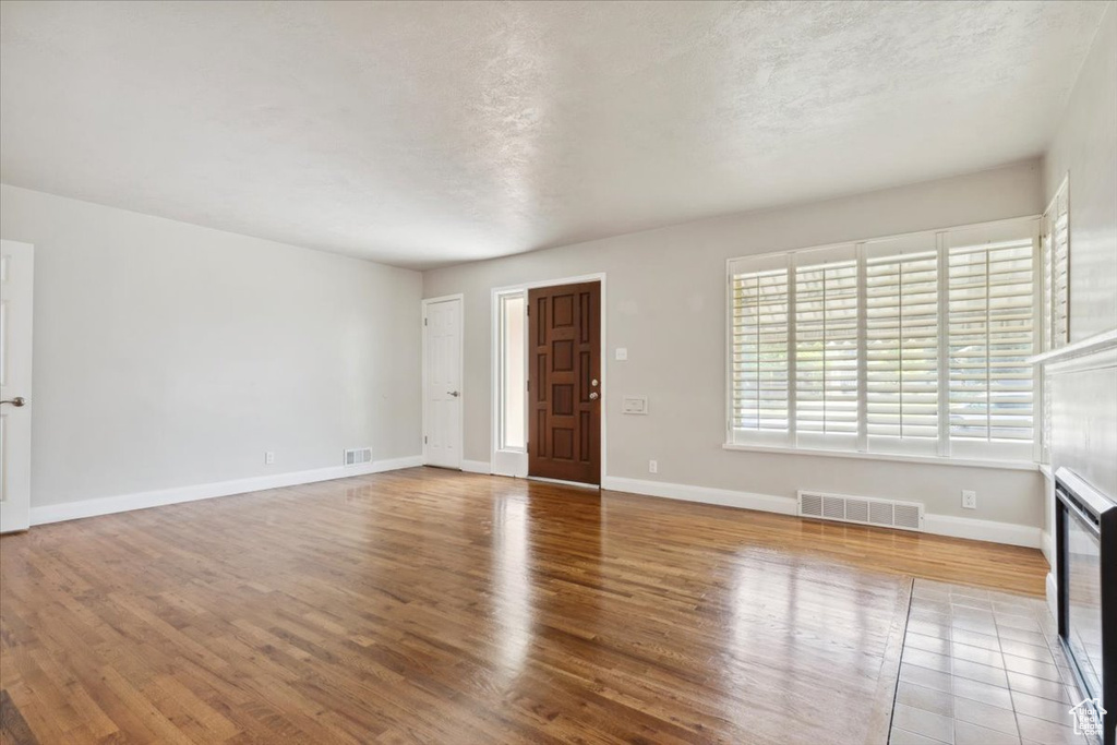 Unfurnished living room featuring wood finished floors and a textured ceiling