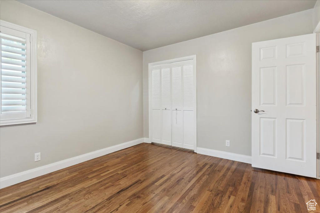Unfurnished bedroom featuring dark wood-style floors and a closet