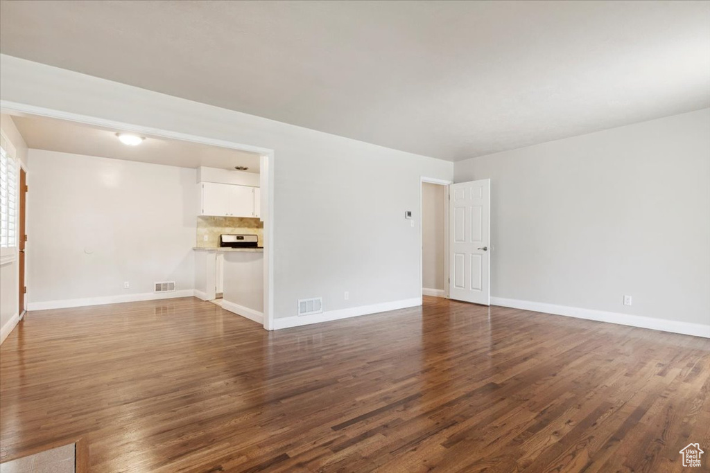 Unfurnished living room featuring dark wood-style floors and baseboards
