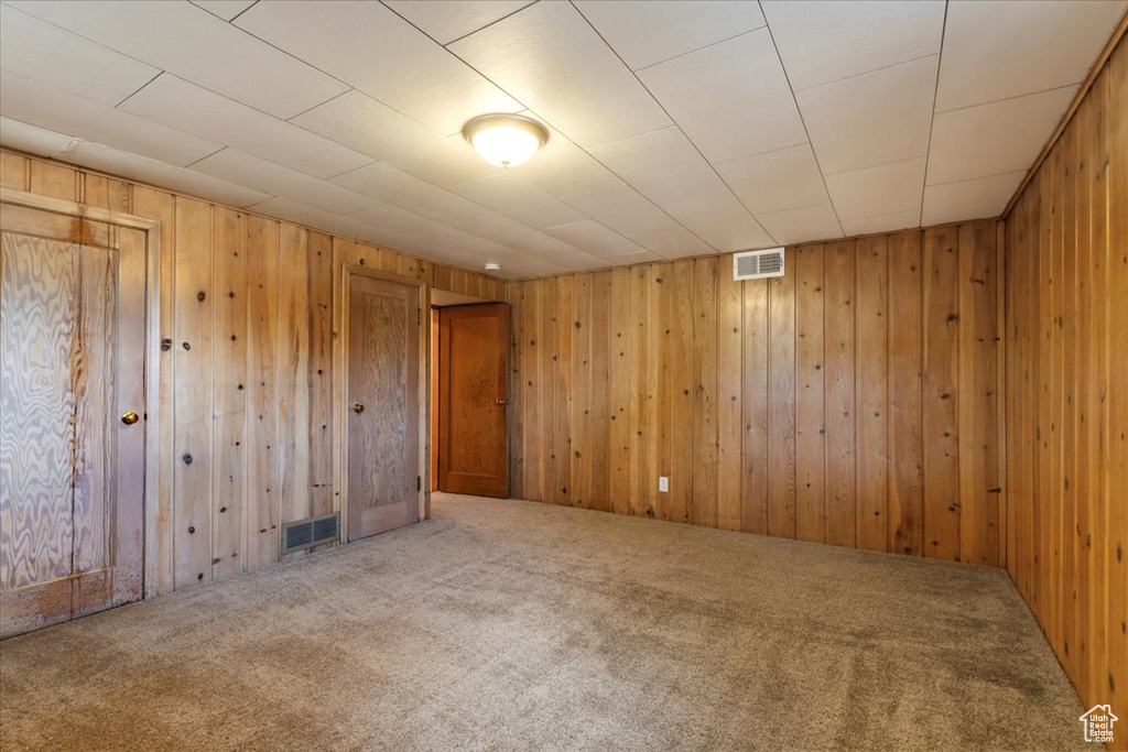 Carpeted spare room featuring wooden walls