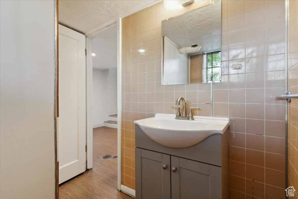 Bathroom with tile walls, vanity, wood finished floors, and a textured ceiling