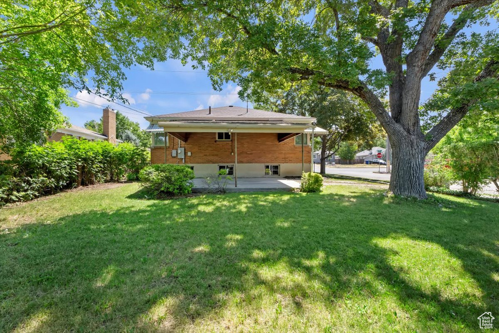 Back of house with a patio and a lawn