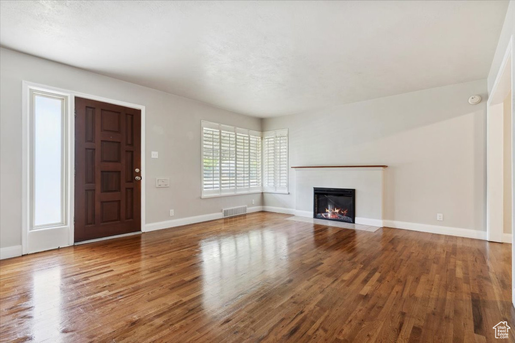 Unfurnished living room with wood finished floors and a fireplace with flush hearth