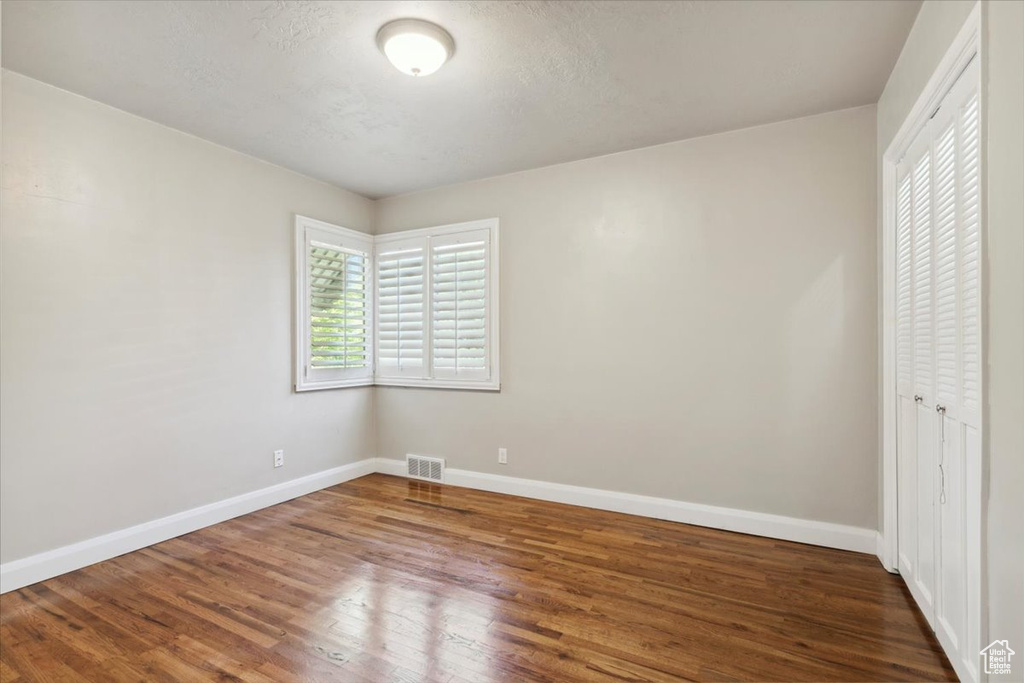 Unfurnished bedroom with wood finished floors and a closet