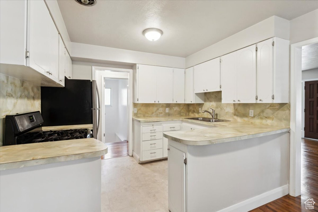 Kitchen featuring appliances with stainless steel finishes, light countertops, tasteful backsplash, and white cabinets