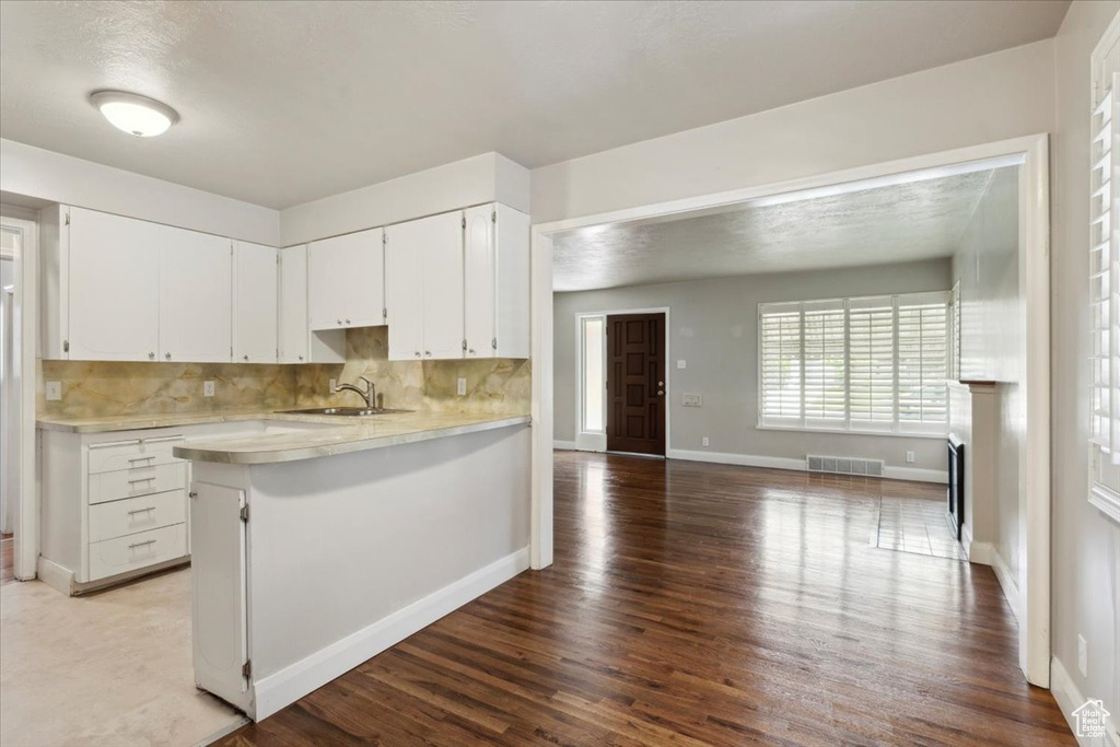 Kitchen featuring light countertops, wood finished floors, white cabinets, and tasteful backsplash