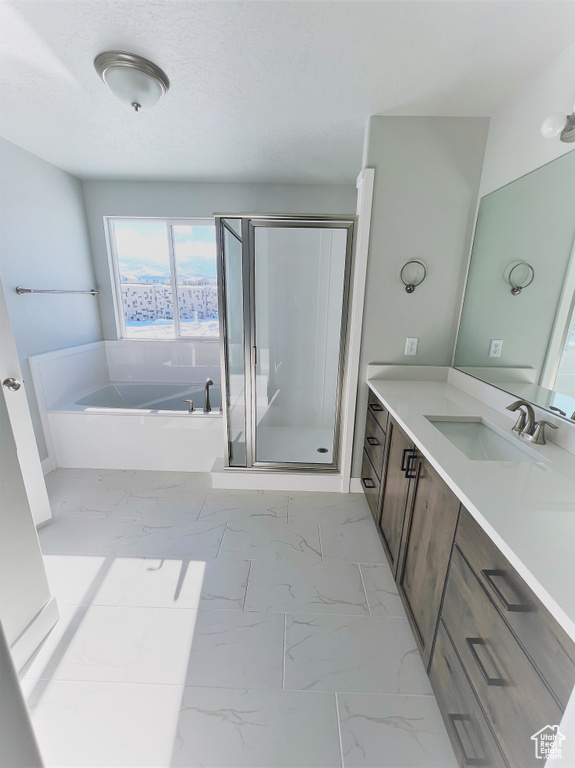 Bathroom featuring marble finish flooring, vanity, a stall shower, and a garden tub