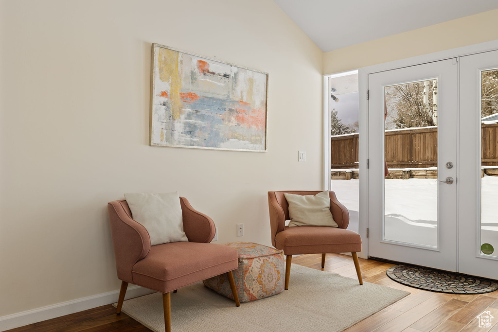 Living area with french doors, wood finished floors, and vaulted ceiling