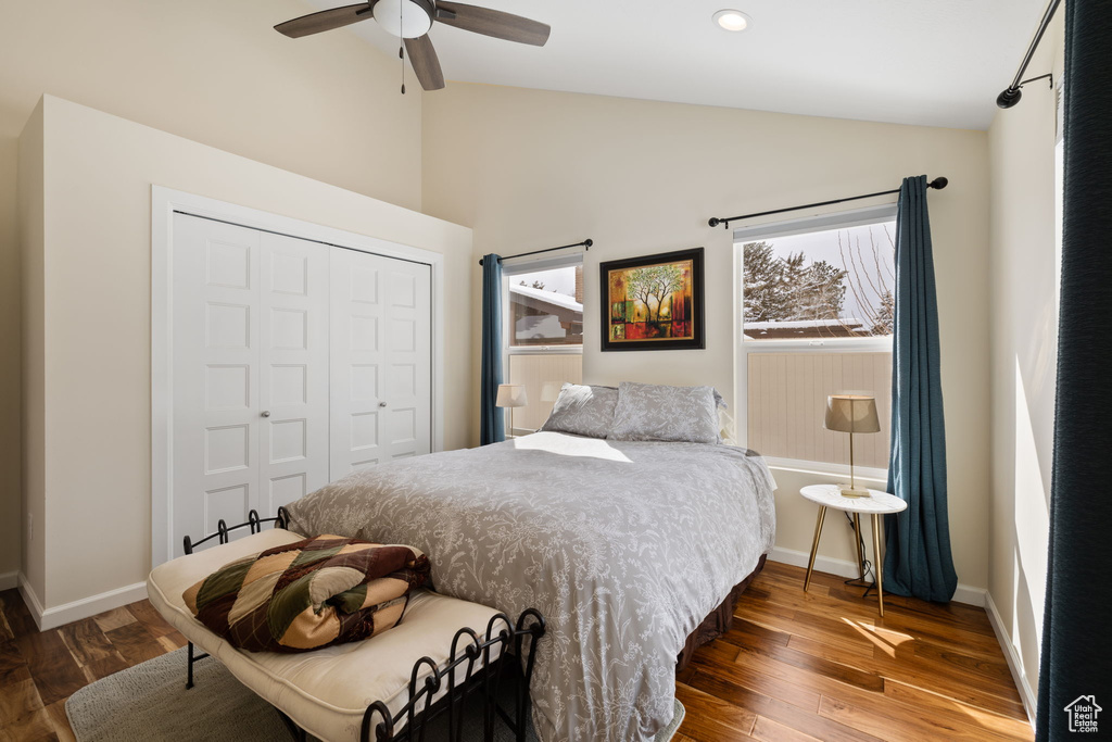 Bedroom with lofted ceiling, a closet, wood finished floors, and a ceiling fan