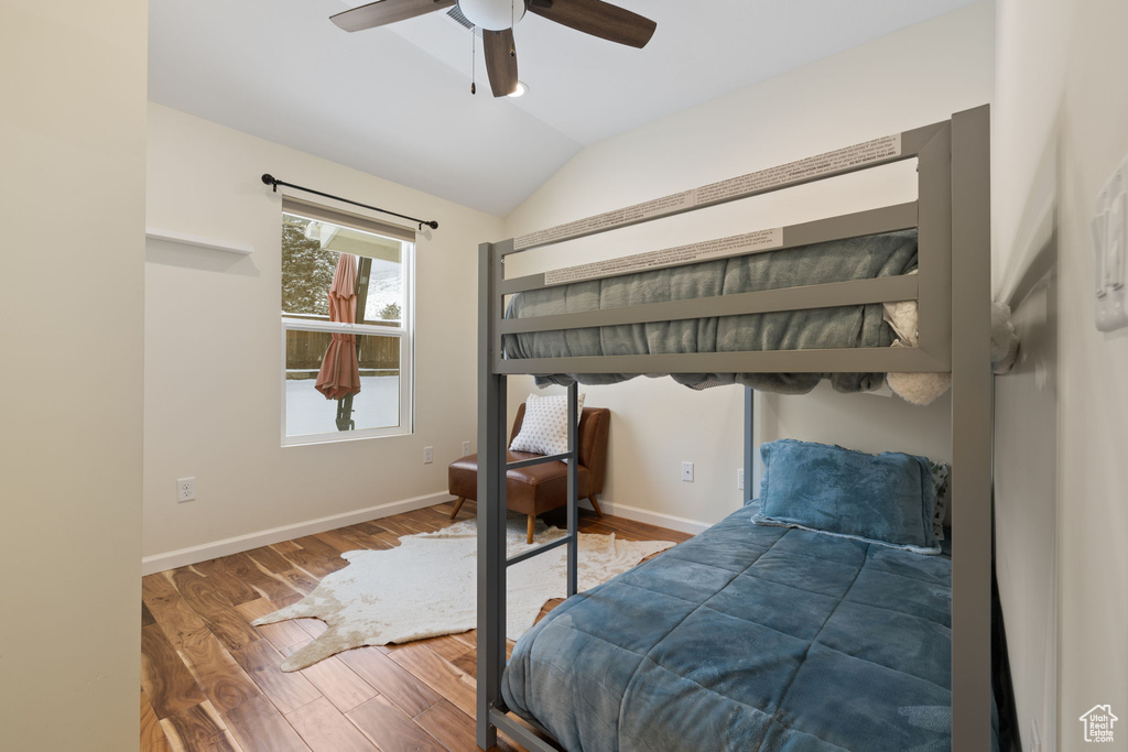 Bedroom with vaulted ceiling, wood finished floors, and ceiling fan