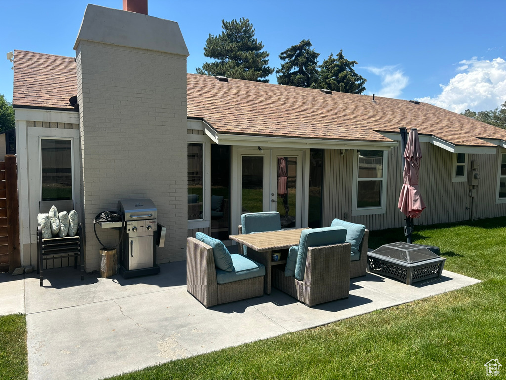 Back of house with a shingled roof, a patio, french doors, a chimney, and a yard