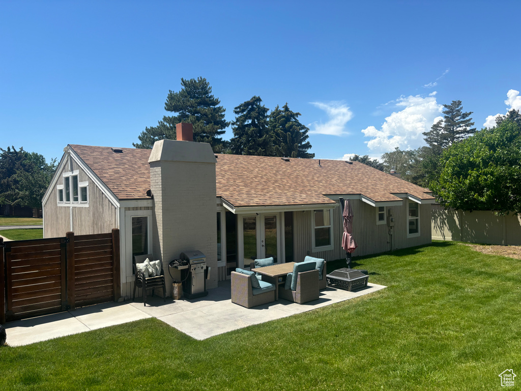 Rear view of property featuring a shingled roof, a chimney, and a patio
