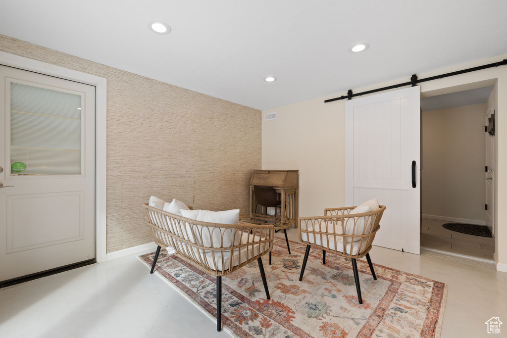 Living area featuring a barn door, recessed lighting, wallpapered walls, and an accent wall