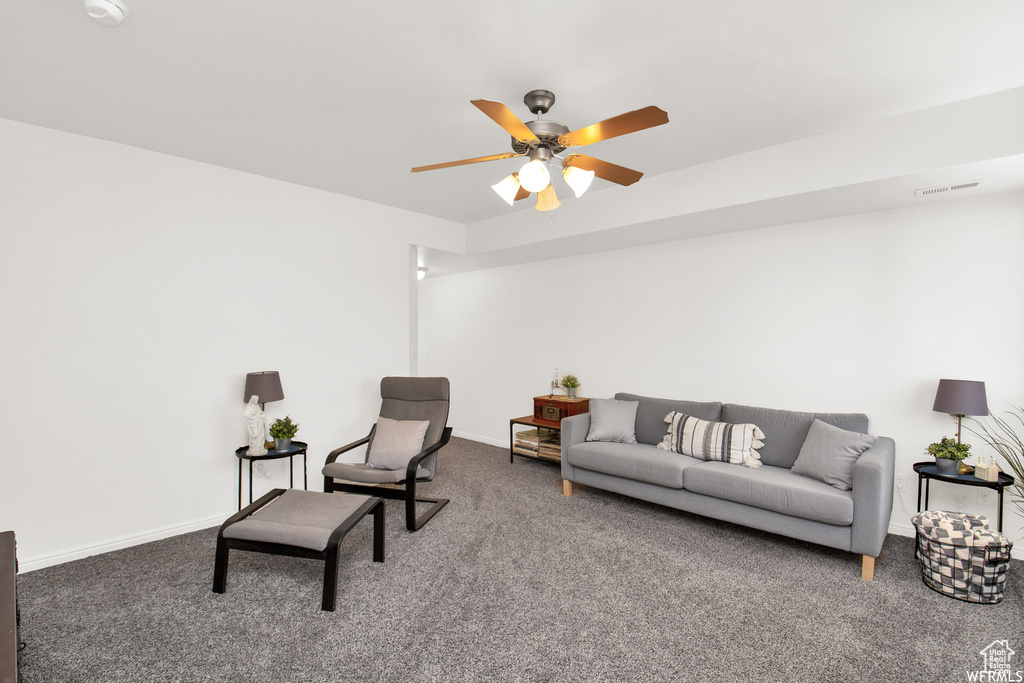 Carpeted living room with ceiling fan and baseboards