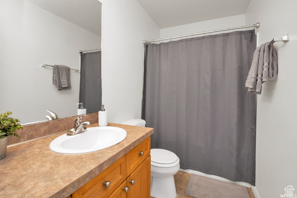 Bathroom with toilet, vanity, curtained shower, and tile patterned floors