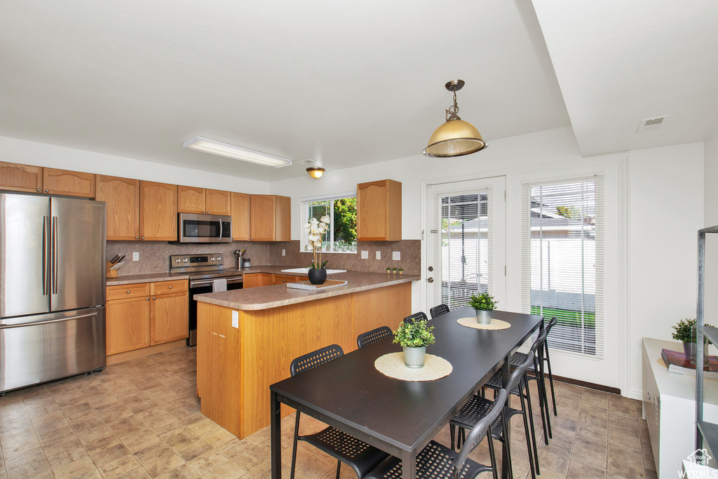 Kitchen featuring stainless steel appliances, backsplash, a sink, and decorative light fixtures