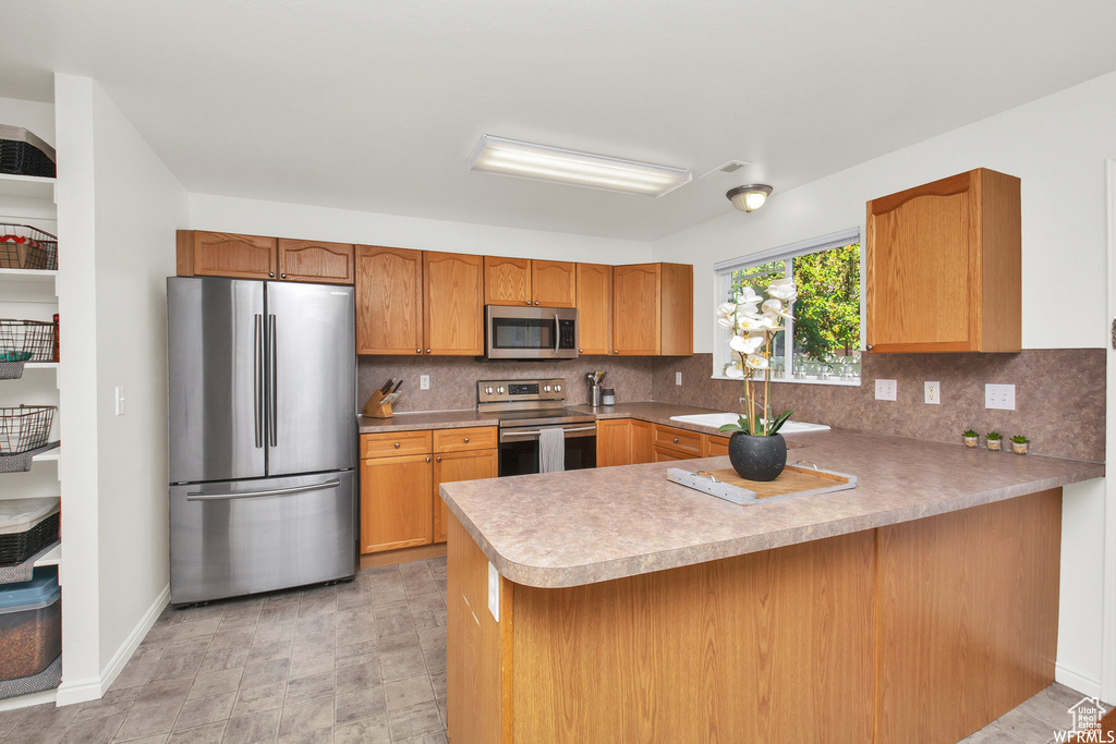 Kitchen with stainless steel appliances, a peninsula, a sink, and tasteful backsplash