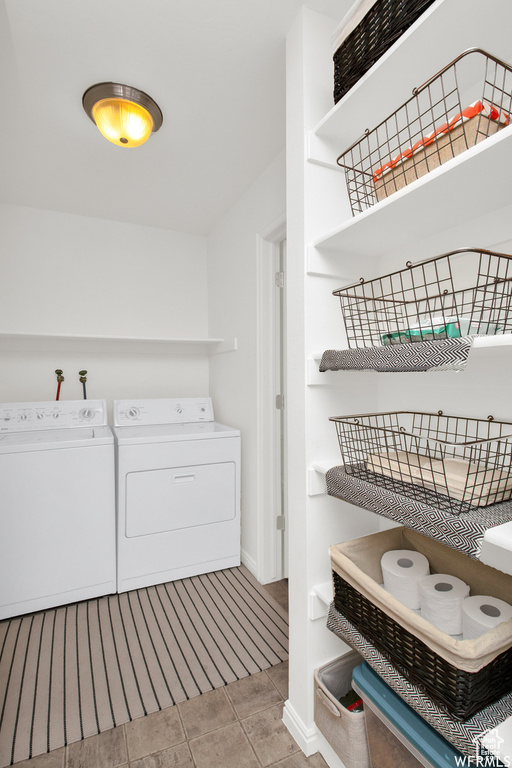 Washroom with washing machine and dryer, baseboards, and tile patterned flooring