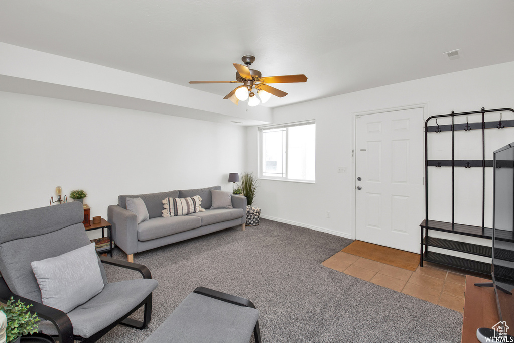Carpeted living room with a ceiling fan, tile patterned floors, and baseboards